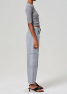 Person wearing light gray cargo pants and a cropped top on a white background