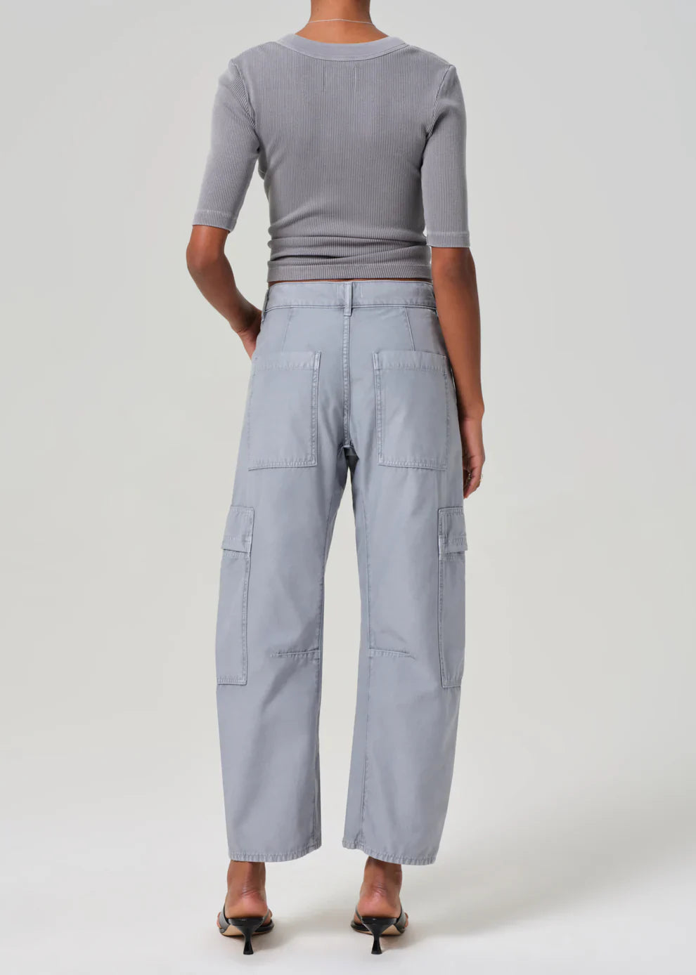 Person wearing a gray outfit with wide-leg pants on a white background