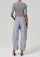 Person wearing a gray outfit with wide-leg pants on a white background