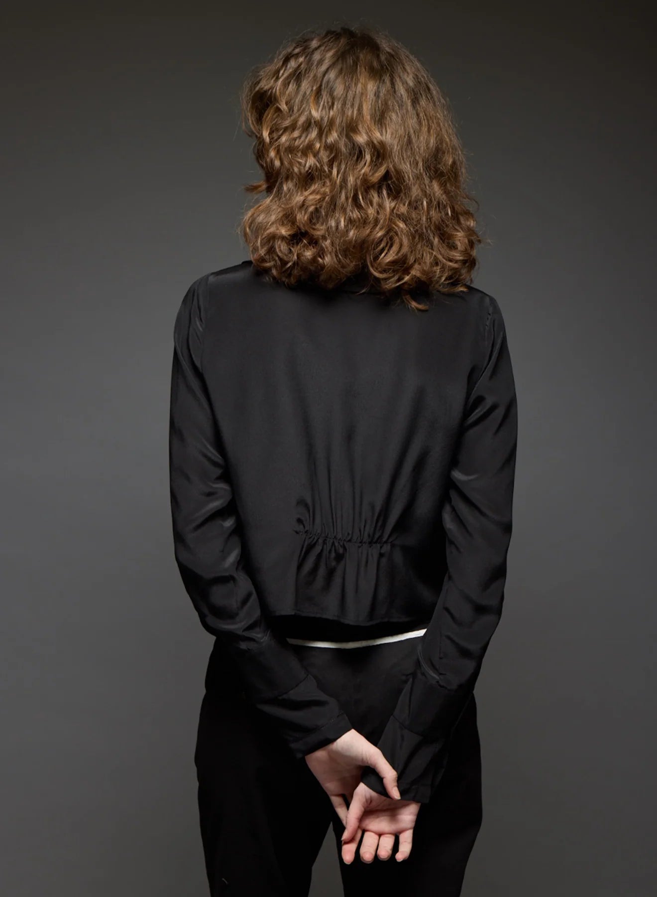 Person wearing a black outfit against a gray background