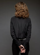 Person wearing a black outfit against a gray background