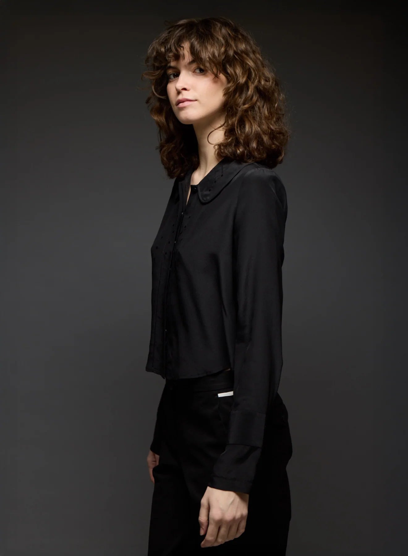 Woman wearing a black blouse against a dark background
