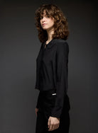 Woman wearing a black blouse against a dark background