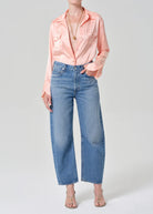 Person wearing a pink blouse and blue jeans on a white background