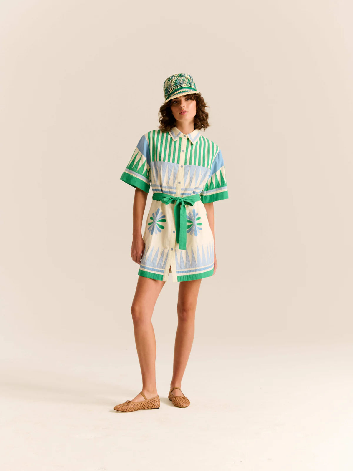 Person wearing a green and white striped outfit with a matching hat on a beige background
