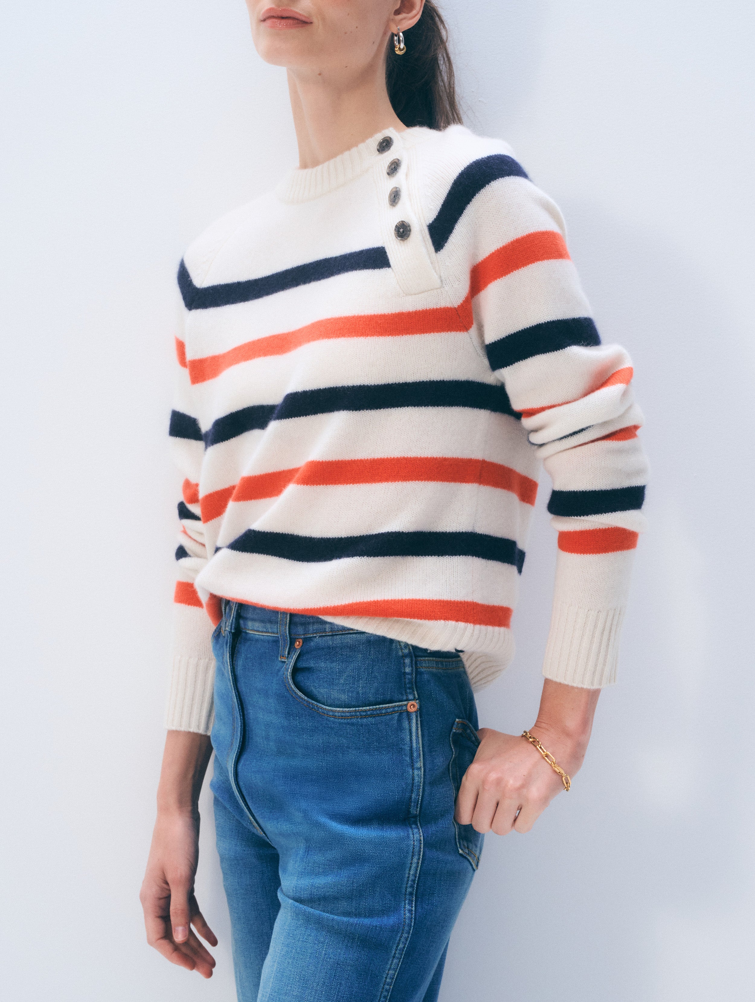 Person wearing a striped sweater with blue jeans against a white background