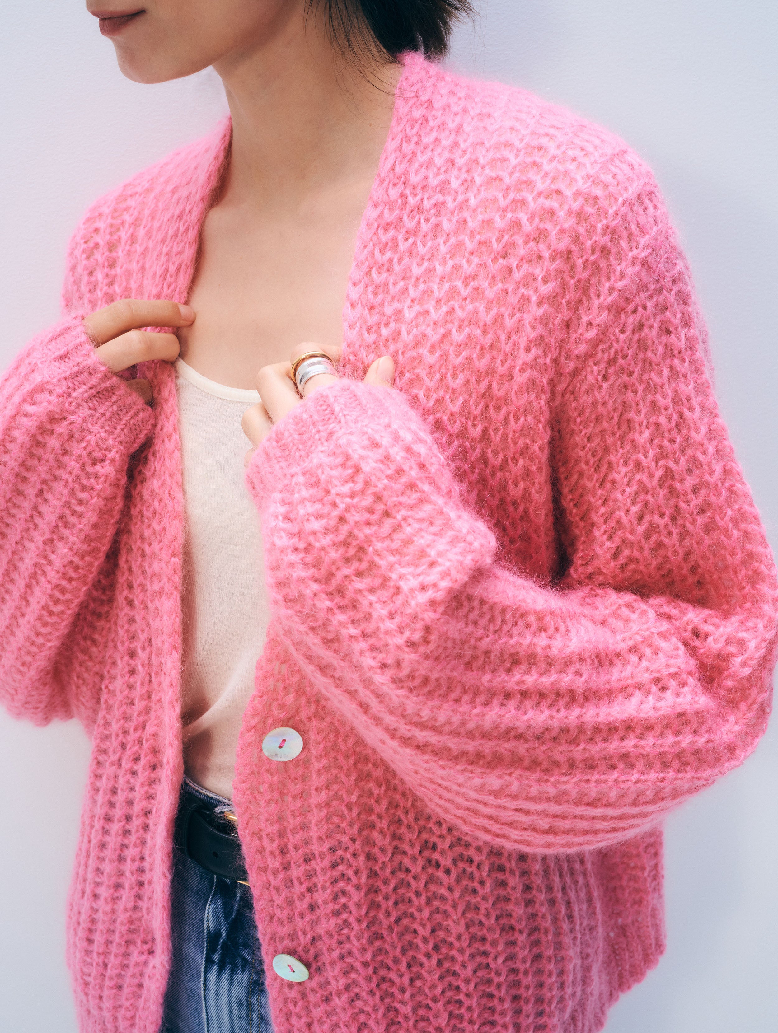 Person wearing a pink knitted cardigan against a light background