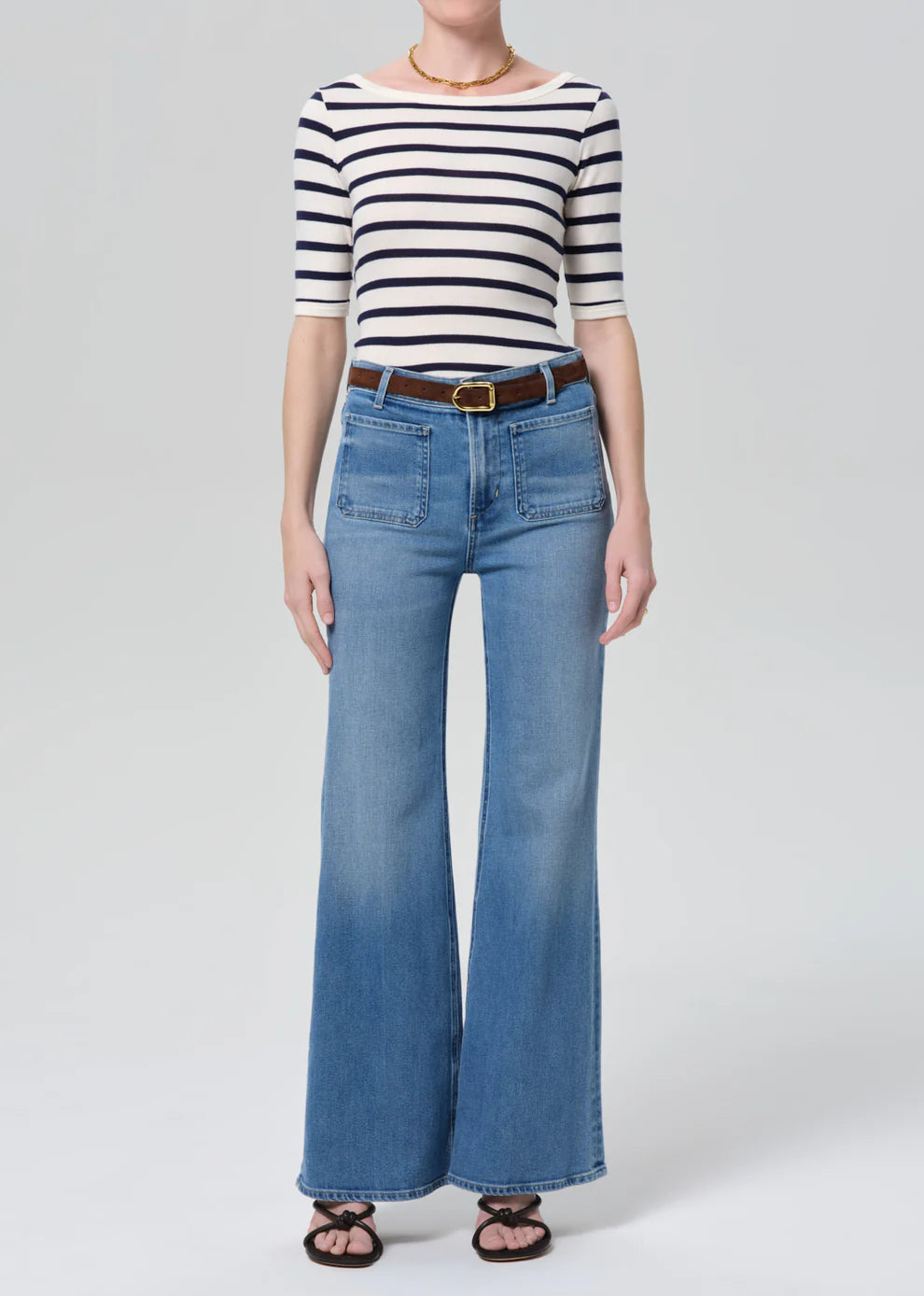 Person wearing a striped shirt and blue jeans on a white background