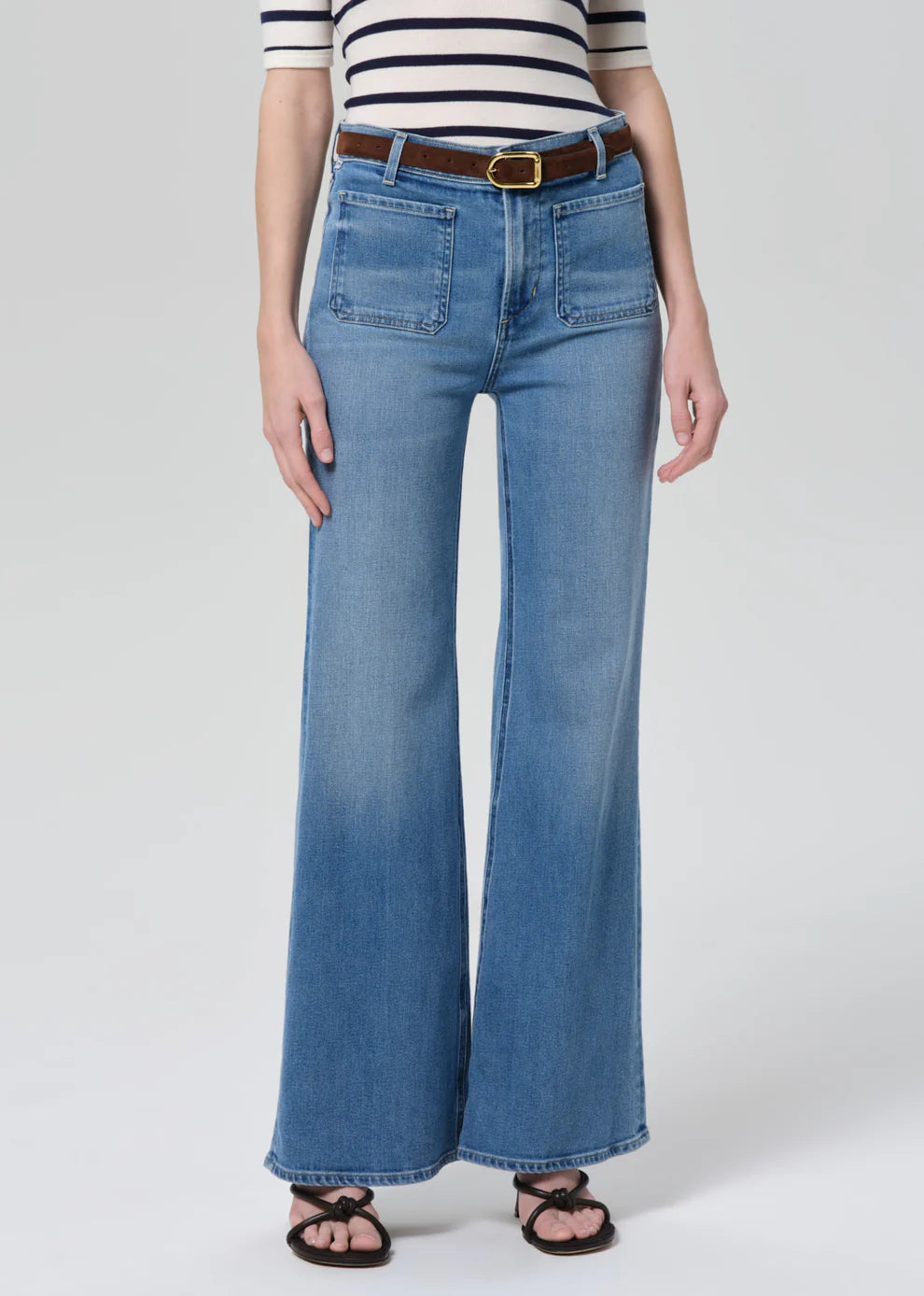 Person wearing blue jeans and a striped shirt on a white background