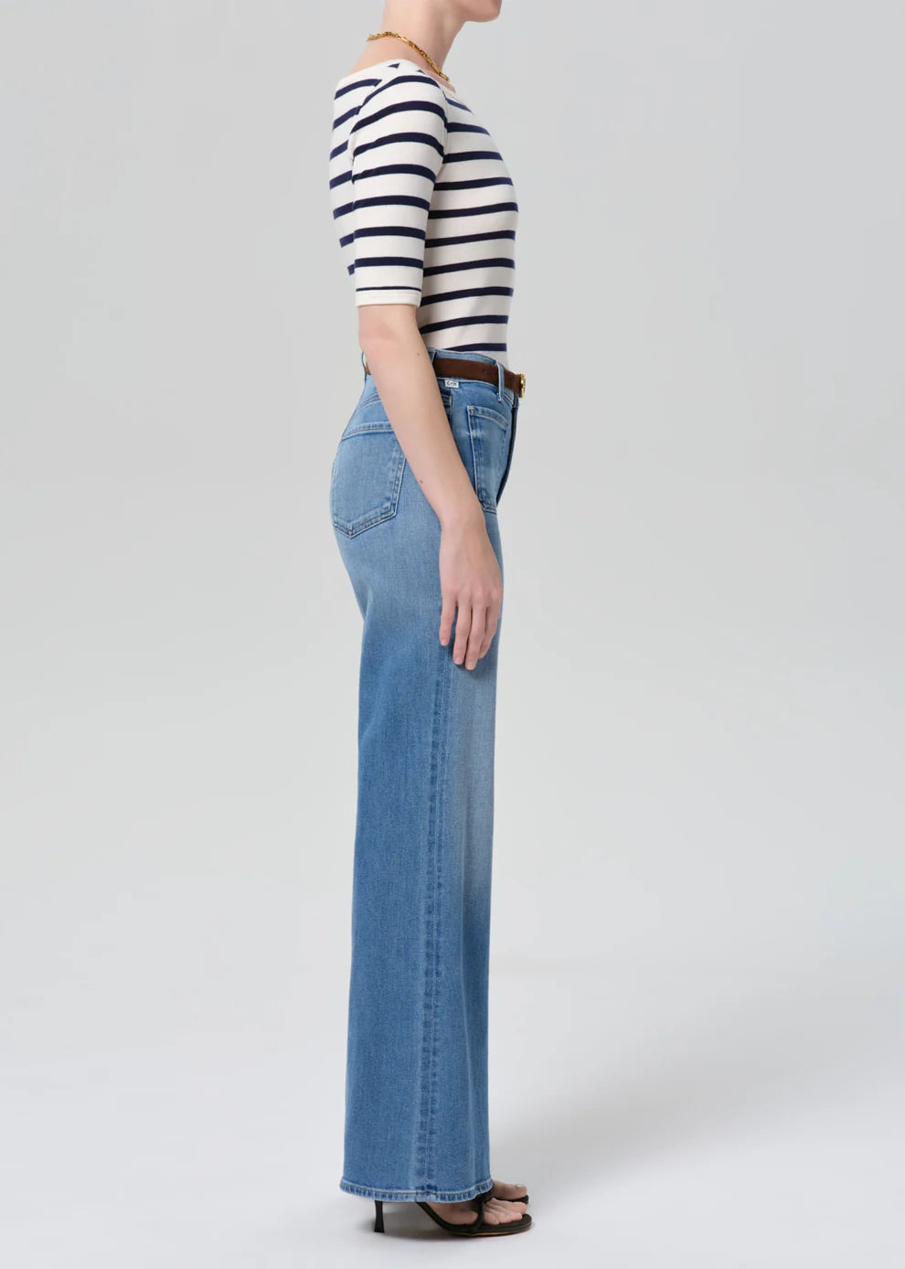 Person wearing a striped shirt and blue jeans on a white background