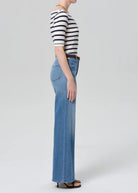 Person wearing a striped shirt and blue jeans on a white background