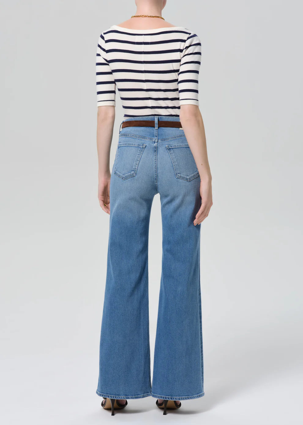 Person wearing a striped shirt and blue jeans on a white background