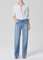 Person wearing a light blue shirt and jeans on a white background