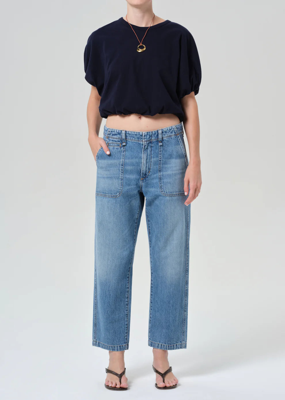 Person wearing a navy top and light blue jeans on a white background
