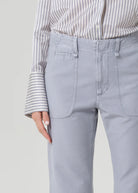 Person wearing light gray pants and a striped shirt on a plain background