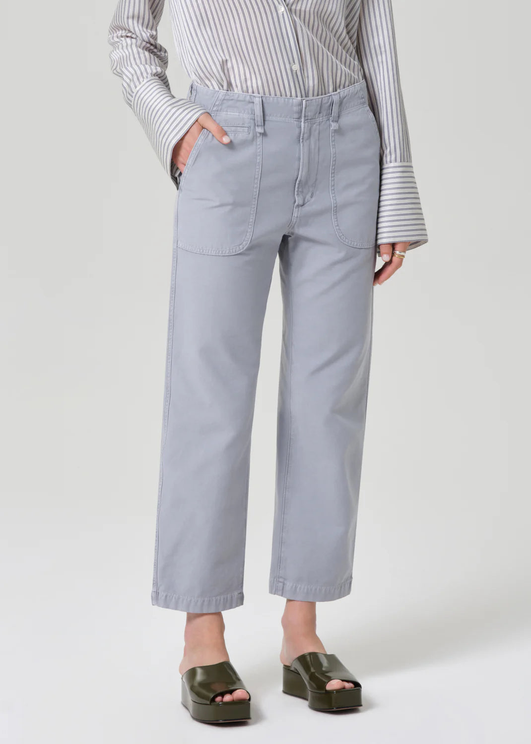 Person wearing light gray pants and a striped shirt on a white background