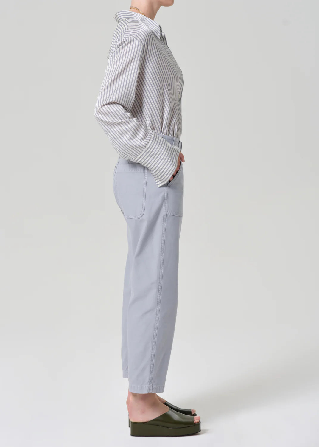 Person wearing a striped shirt and light gray pants on a white background