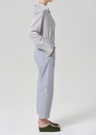 Person wearing a striped shirt and light gray pants on a white background