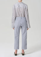 Person wearing a striped shirt and light gray pants on a white background