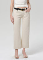 Person wearing beige wide-leg pants with a white top on a plain background