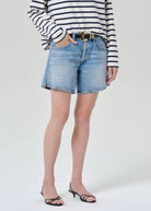 Person wearing a striped shirt and denim shorts on a white background
