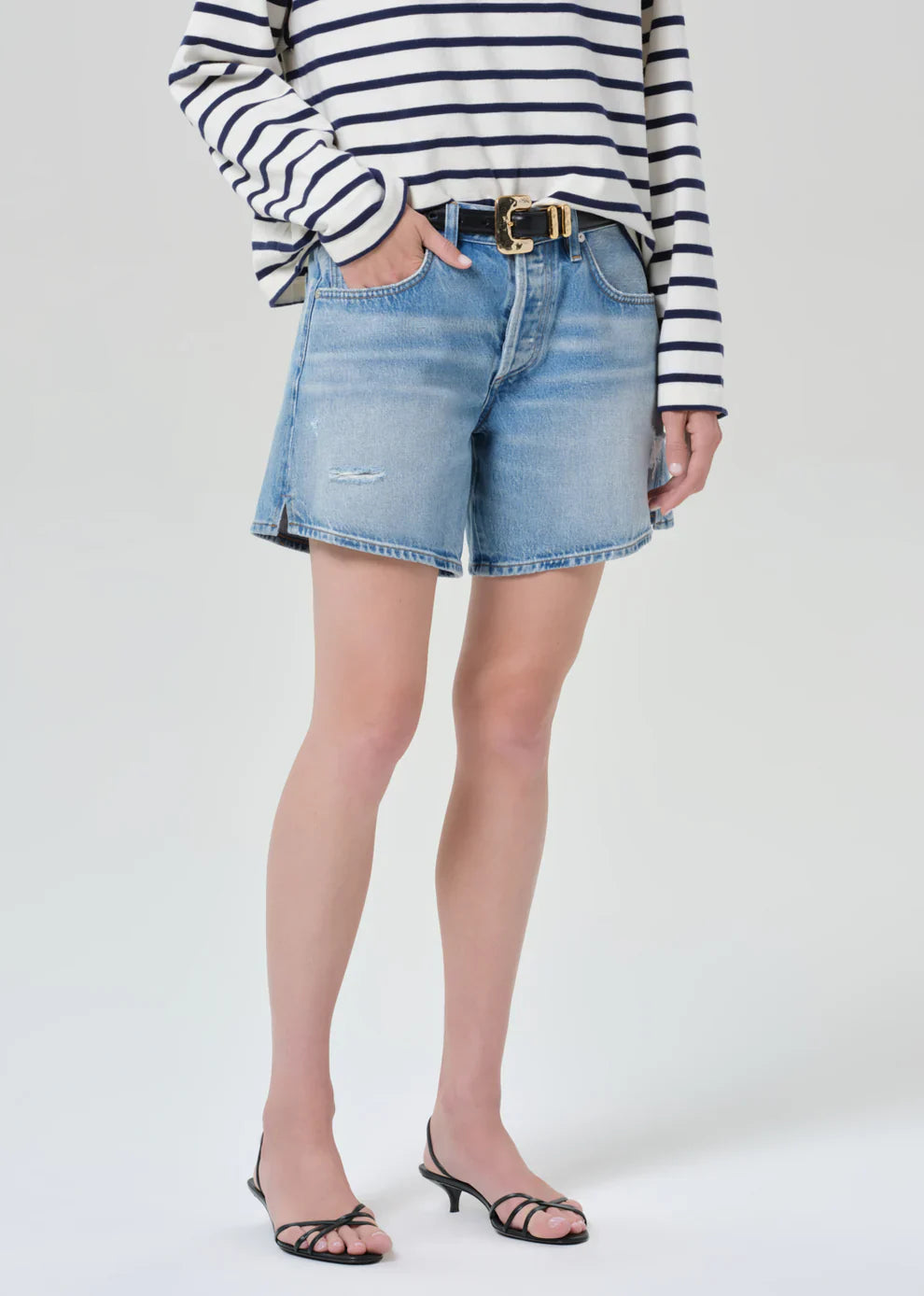 Person wearing a striped shirt and denim shorts on a white background