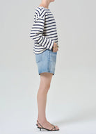 Person wearing a striped sweater and denim shorts on a plain background