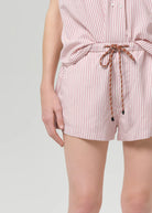 Person wearing a pink and white striped romper with a tie waist on a light gray background