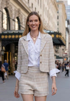 Woman in a stylish outfit with a textured jacket and shorts on a city street.