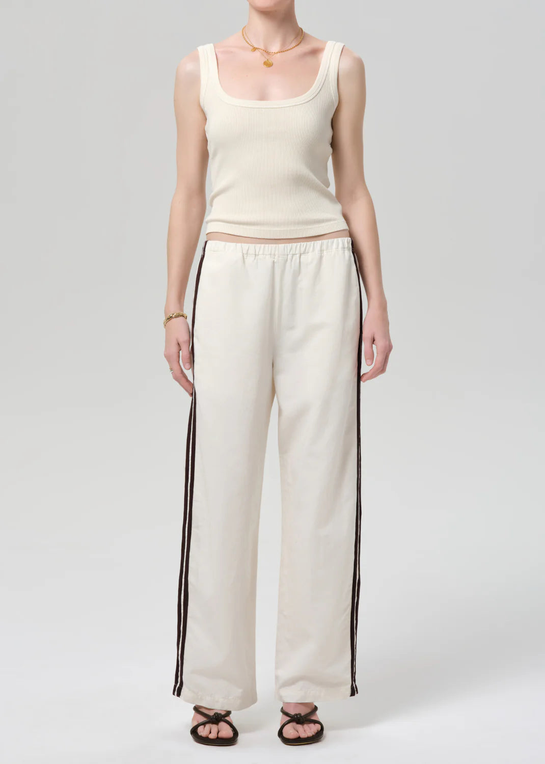 Person wearing a cream tank top and wide-leg pants with black stripes on a white background