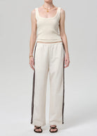 Person wearing a cream tank top and wide-leg pants with black stripes on a white background