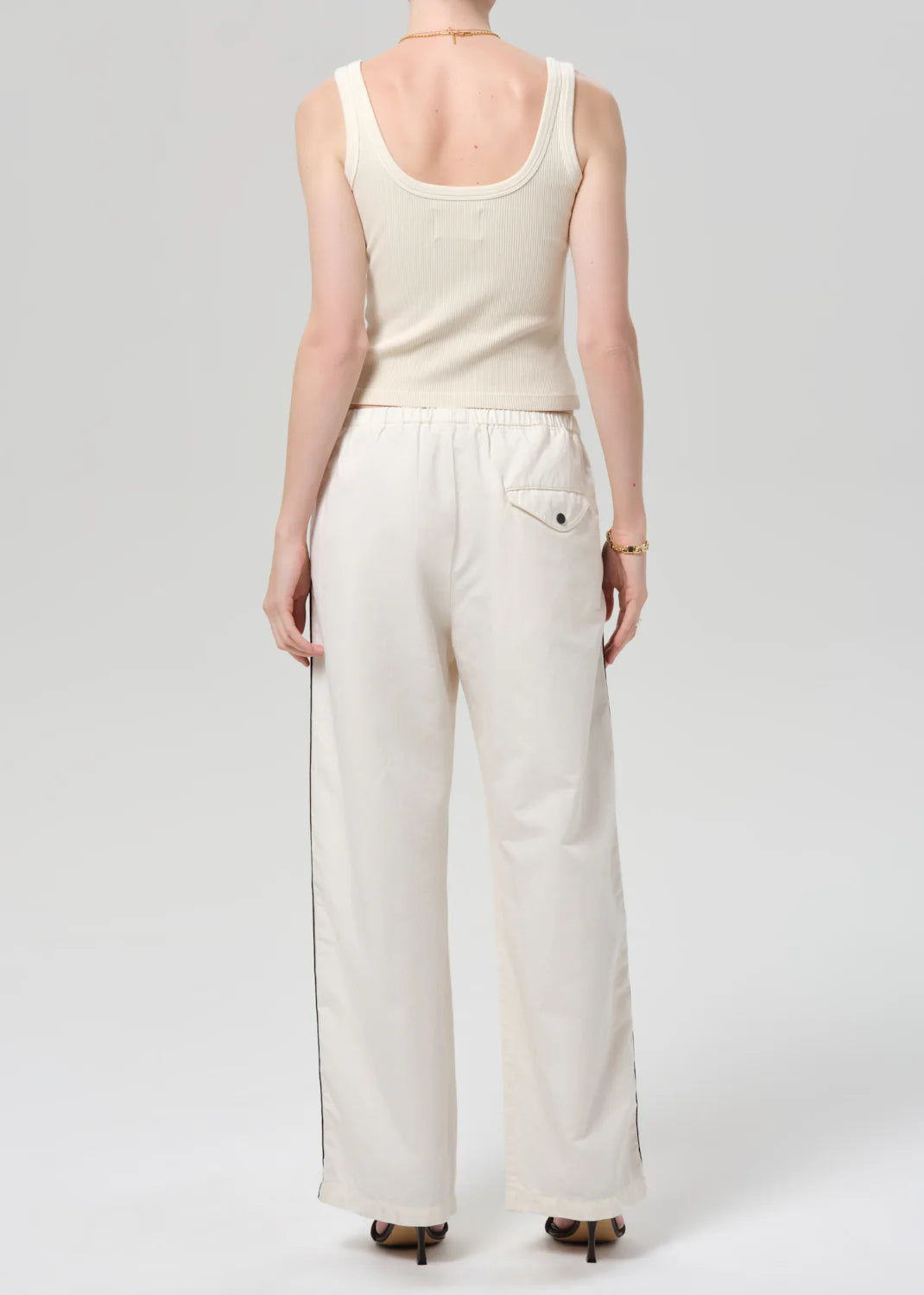 Person wearing a white tank top and wide-leg pants on a plain background