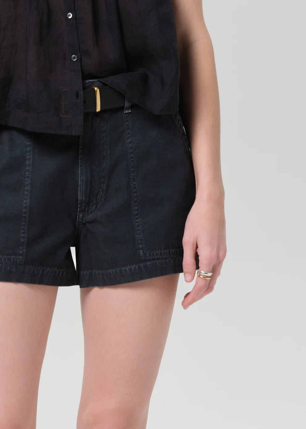 Person wearing black shorts and a black shirt on a plain background