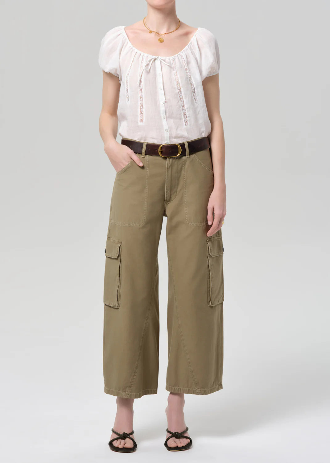 Person wearing a white blouse and beige cargo pants on a plain background