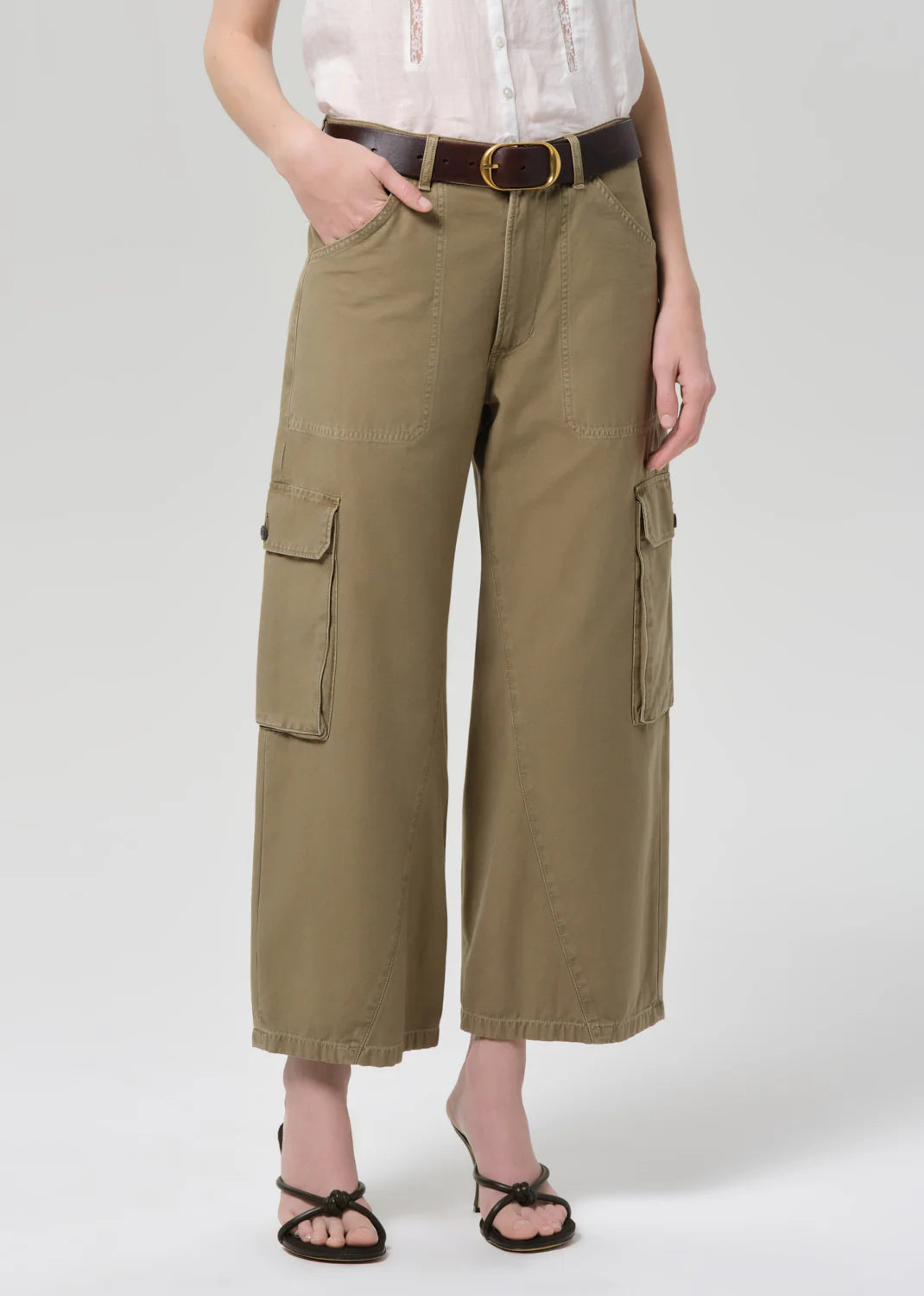 Person wearing olive green cargo pants on a white background