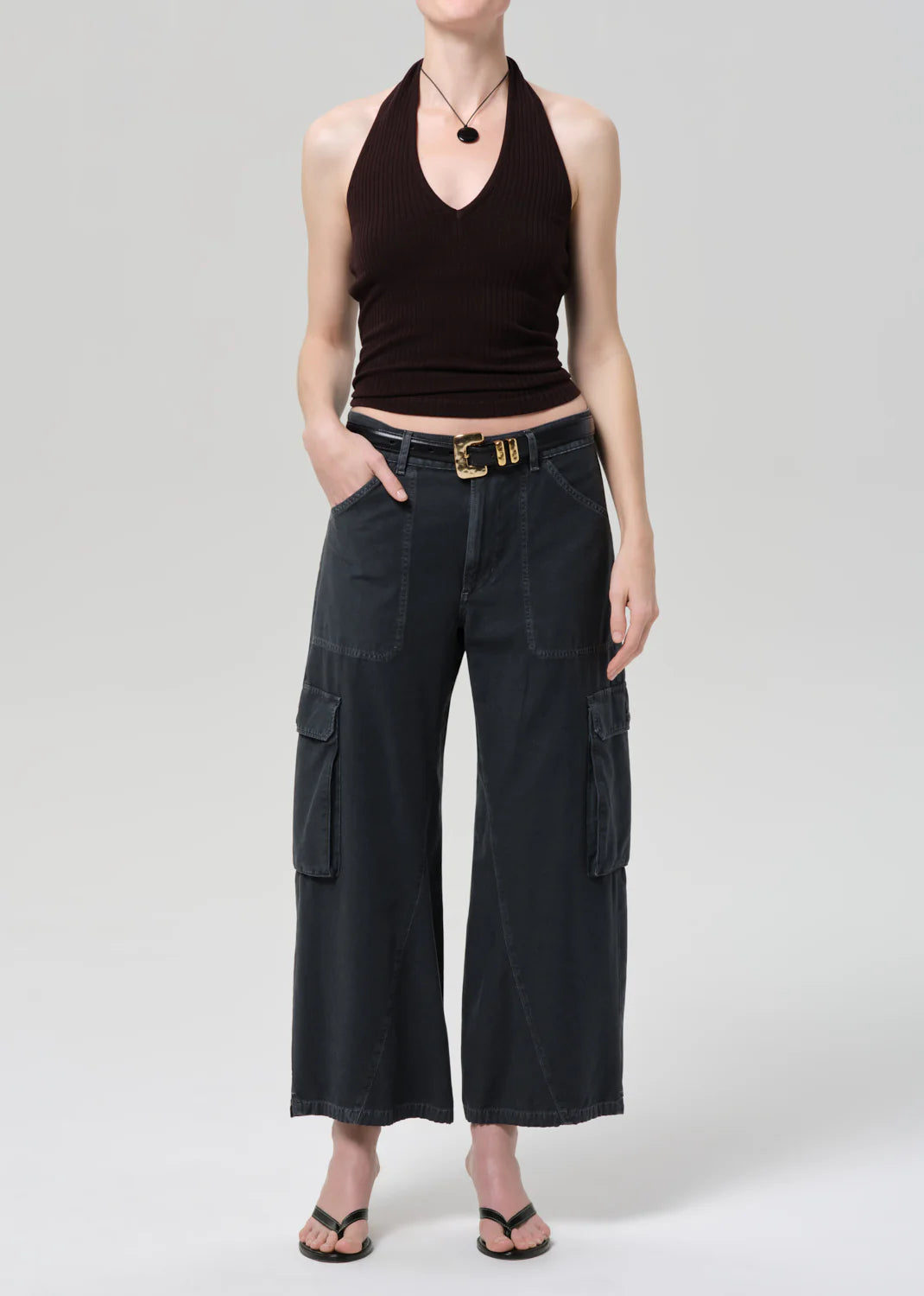 Person wearing black halter top and wide-leg cargo pants on a plain background