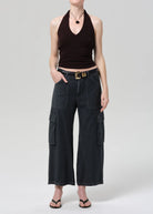 Person wearing black halter top and wide-leg cargo pants on a plain background