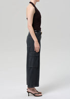 Person wearing black sleeveless top and cargo pants on a white background
