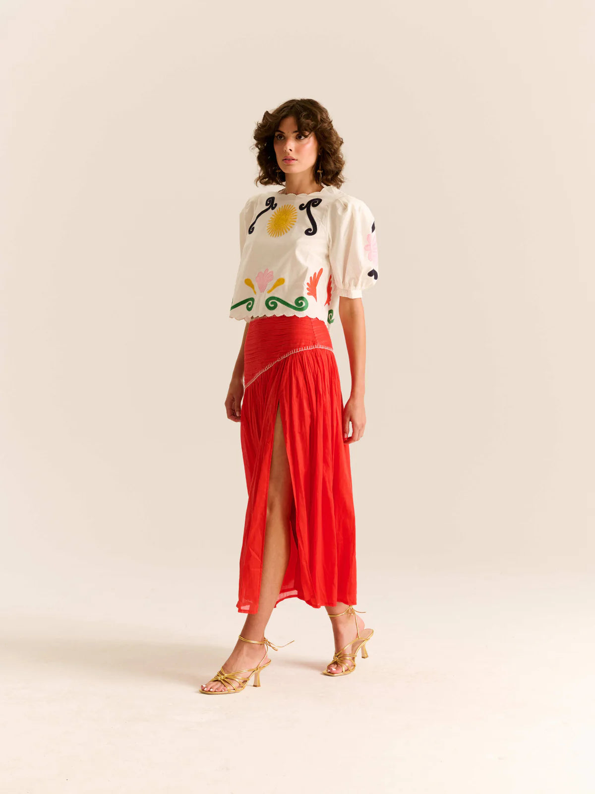 Woman wearing a colorful top and red skirt on a beige background