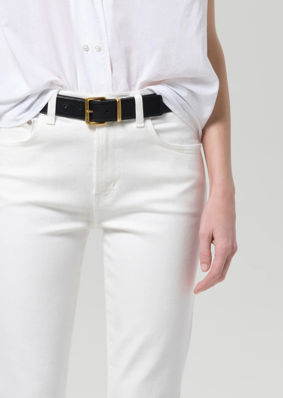 Person wearing a white shirt and white pants on a plain background