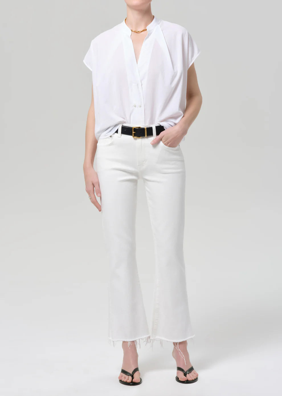Person wearing a white shirt and white pants on a plain background