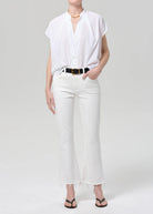 Person wearing a white shirt and white pants on a plain background