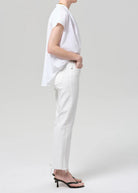 Person wearing a white shirt and white pants on a plain background