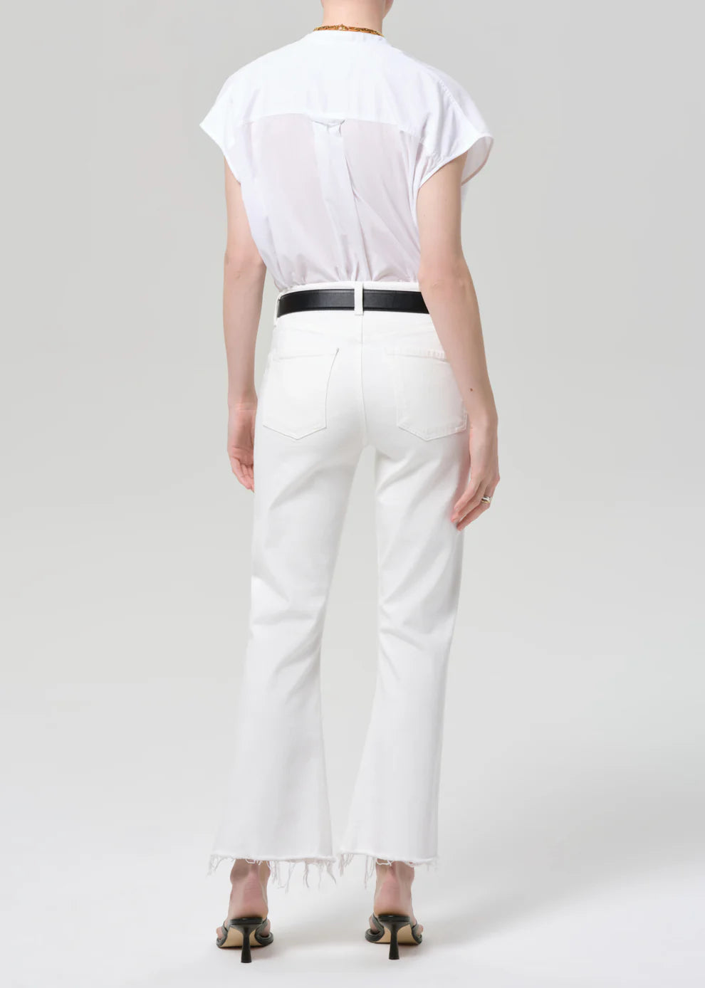Person wearing a white shirt and white pants on a plain background