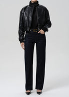 Person wearing a black leather jacket, black turtleneck, black jeans, and black shoes on a white background