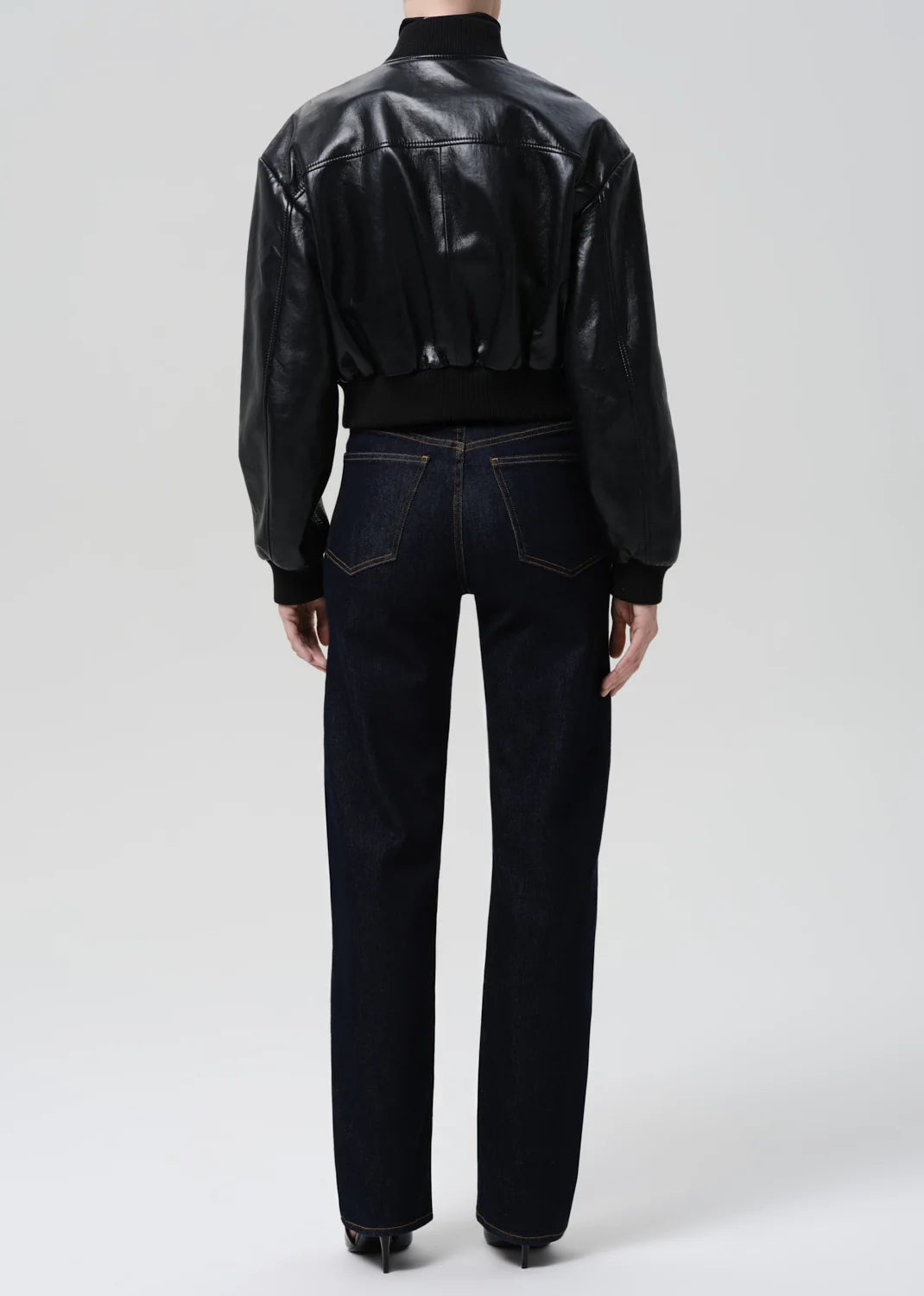 Person wearing a black leather jacket and dark jeans on a white background