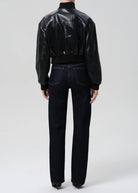 Person wearing a black leather jacket and dark jeans on a white background