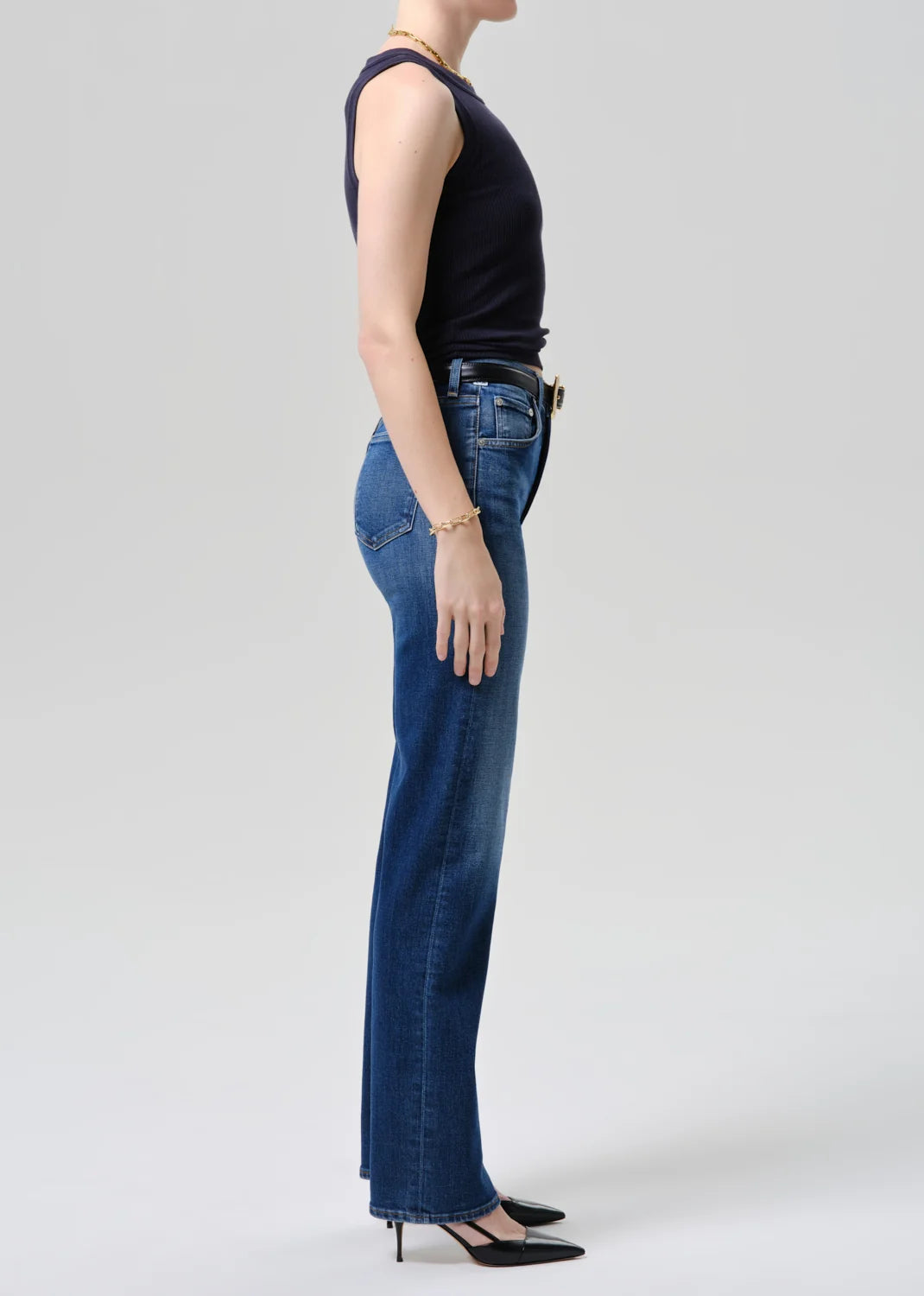 Person wearing blue jeans and a dark top on a white background