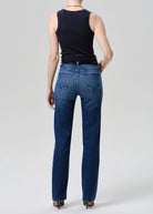 Person wearing blue jeans and a black sleeveless top on a white background