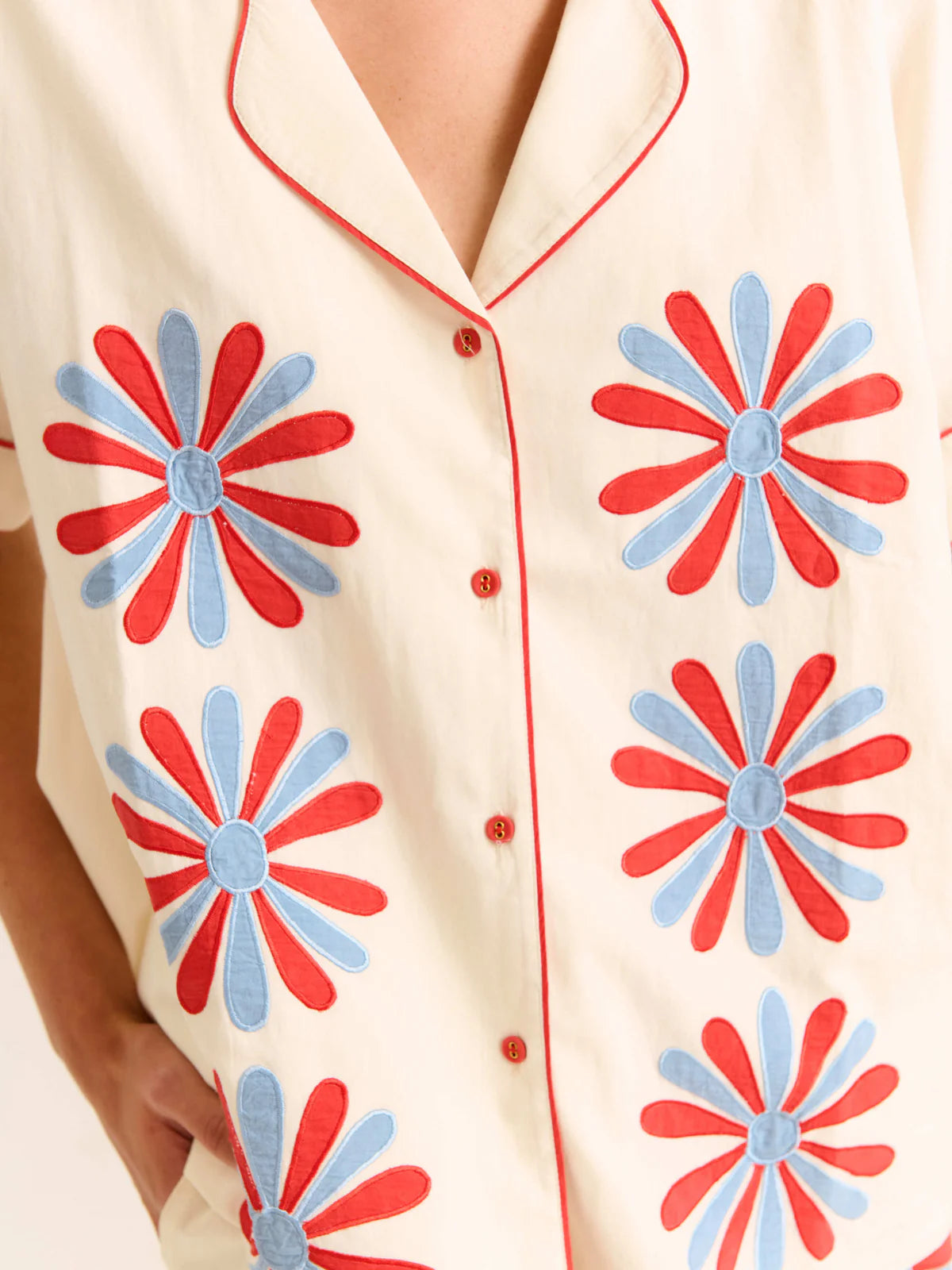 Beige shirt with red and blue floral patterns on a white background